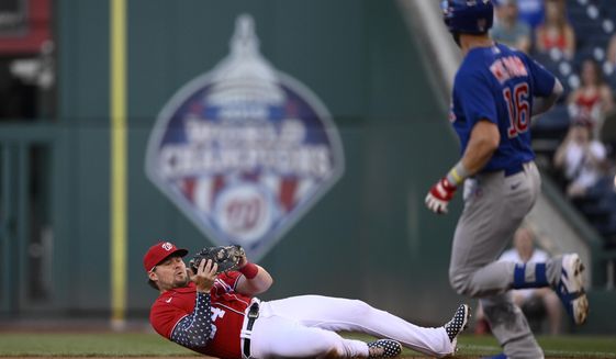 Washington Nationals first baseman Luke Voit, left, falls to the ground after he caught a popup by Chicago Cubs&#39; Patrick Wisdom (16) during the first inning of a baseball game Tuesday, Aug. 16, 2022, in Washington. (AP Photo/Nick Wass)