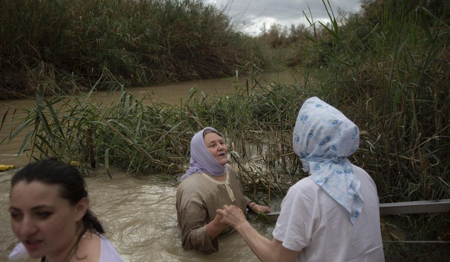 FILE - Christian pilgrims stand in the waters of the Jordan River during a baptism ceremony as part of the Orthodox Feast of the Epiphany at the Qasr al-Yahud baptismal site, near the West Bank town of Jericho, on Friday, Jan. 19, 2018. Tourists and pilgrims come to the river from near and far, many driven by faith, to follow in Christ’s footsteps, to touch its water, to conjure up biblical events. (AP Photo/Oded Balilty)