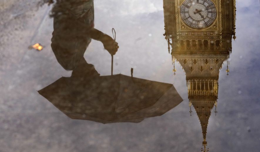 A woman with an umbrella and the Elizabeth Tower also known as Big Ben are reflected in a puddle in London, Tuesday, Aug. 16, 2022. (AP Photo/Frank Augstein) ** FILE **