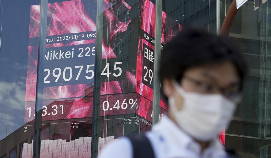 A person wearing a protective mask walks in front of an electronic stock board showing Japan&#39;s Nikkei 225 index Friday, Aug. 19, 2022, in Tokyo. Asian stock markets were mixed Friday after Wall Street rose as investors analyzed conflicting economic signals ahead of a Federal Reserve conference next week. (AP Photo/Eugene Hoshiko)