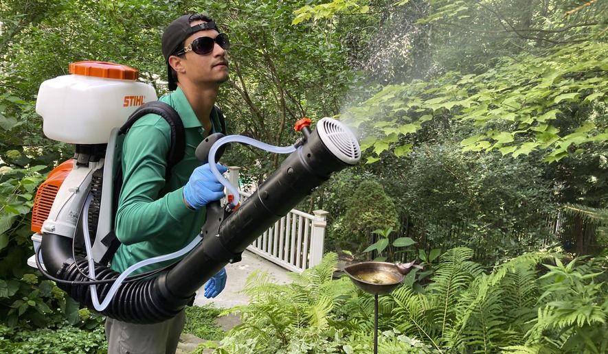 Mosquito Joe lead technician Damien Ysasi sprays a mixture of essential oil insecticides in a yard in Cascade Township near Grand Rapids, Mich., on July 20, 2022.  As climate change widens the insect&#39;s range and lengthens its prime season, more Americans are resorting to the booming industry of professional extermination. But the chemical bombardment worries scientists who fear over-use of pesticides is harming pollinators and worsening a growing threat to birds that eat insects. (AP Photo/John Flesher)