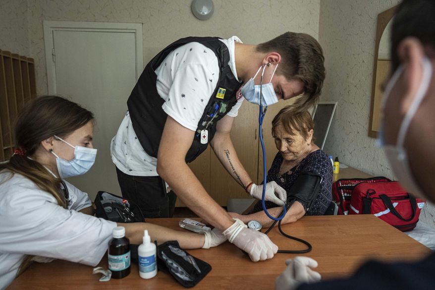 Medics from the Ukrainian Red Cross take the blood pressure of a patient at the center for displaced persons near Mykolaiv, Kharkiv region, Ukraine, on Monday, Aug. 8, 2022. (AP Photo/Evgeniy Maloletka)