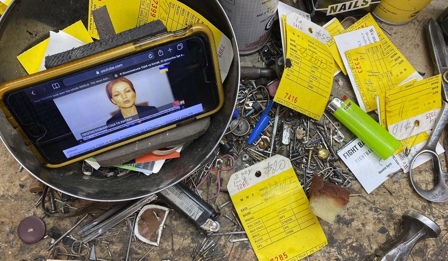 A smartphone plays Ukrainian language news clips at the front counter of Alexander Belanchuk&#39;s workstation in this photograph taken on Tuesday, Aug. 16, 2022, in Colorado Springs, Colo. (Dan Boyce/Colorado Public Radio via AP)