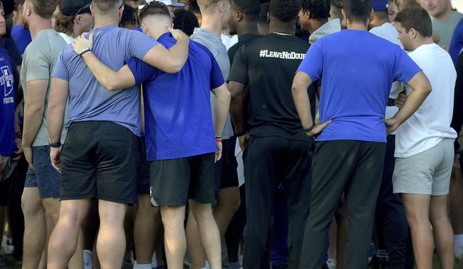 Members of the Indiana State football team console one another after a vigil at Memorial Stadium in Terre Haute, Ind., on Sunday, Aug. 21, 2022, for students, including fellow football players, who were involved in a car crash earlier in the day. (Joseph C. Garza/The Tribune-Star via AP)