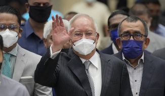 Former Malaysian Prime Minister Najib Razak, center, wearing a face mask, waves as he arrives at the Court of Appeal in Putrajaya, Malaysia, Tuesday, Aug. 23, 2022. Najib was sentenced to 12 years in jail by a high court in July 2020, after being found guilty of abuse of power, criminal breach of trust and money laundering for illegally receiving 42 million ringgit ($9.4 million) from SRC International, a former unit of 1MDB. (AP Photo/Vincent Thian) ** FILE **