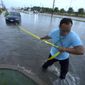 Mon Lun pulls a strap to his water stalled car before towing it out of receding flood waters in Dallas, Monday, Aug. 22, 2022. (AP Photo/LM Otero)