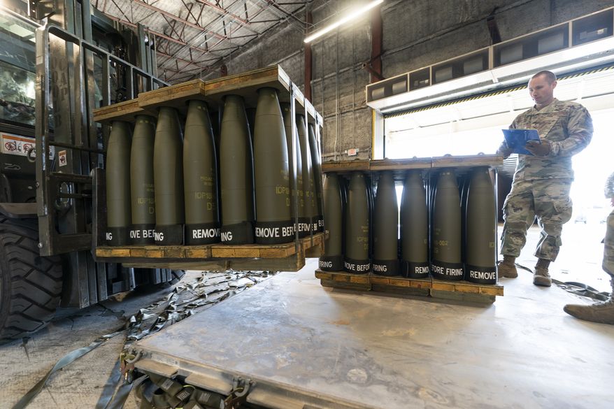 U.S. Air Force Staff Sgt. Cody Brown, right, with the 436th Aerial Port Squadron, checks pallets of 155 mm shells ultimately bound for Ukraine, April 29, 2022, at Dover Air Force Base, Del. (AP Photo/Alex Brandon, File)
