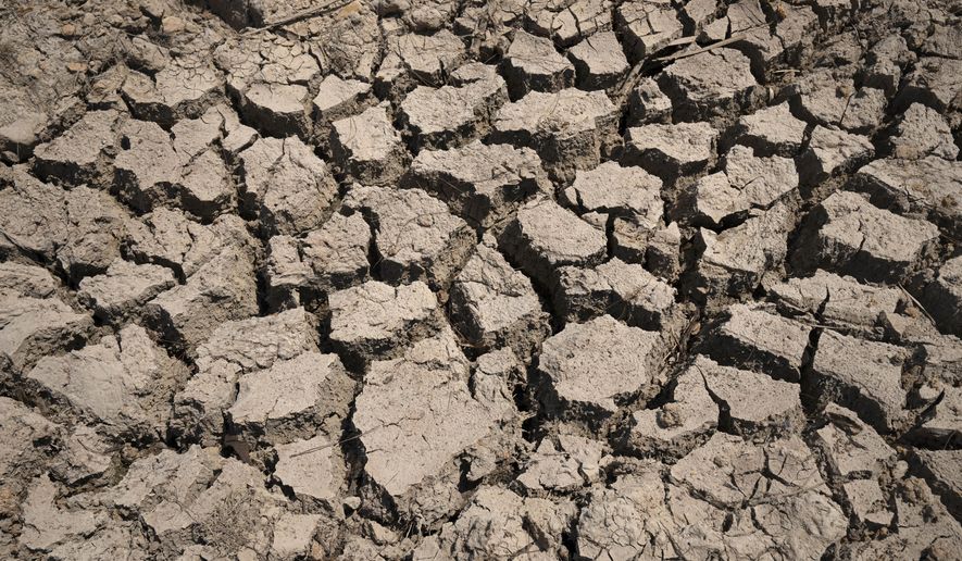 Cracked dry mud is seen in a community reservoir that ran nearly empty after its retaining wall started to leak and hot weather and drought conditions accelerated the loss of water Longquan village in southwestern China's Chongqing Municipality, Saturday, Aug. 20, 2022. The very landscape of Chongqing, a megacity that also takes in surrounding farmland and steep and picturesque mountains, has been transformed by an unusually long and intense heat wave and an accompanying drought. (AP Photo/Mark Schiefelbein, File)