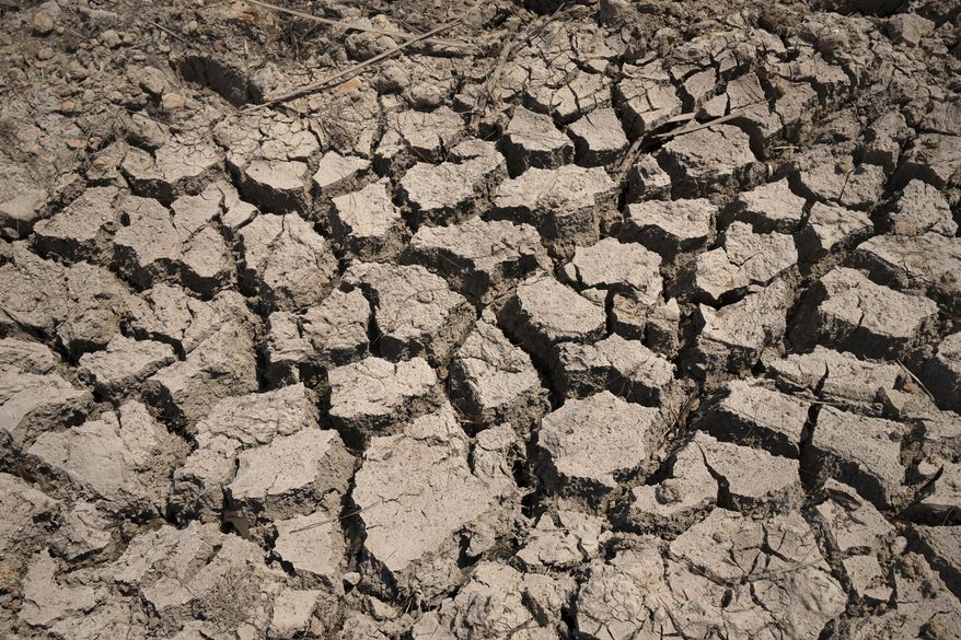 Cracked dry mud is seen in a community reservoir that ran nearly empty after its retaining wall started to leak and hot weather and drought conditions accelerated the loss of water Longquan village in southwestern China's Chongqing Municipality, Saturday, Aug. 20, 2022. The very landscape of Chongqing, a megacity that also takes in surrounding farmland and steep and picturesque mountains, has been transformed by an unusually long and intense heat wave and an accompanying drought. (AP Photo/Mark Schiefelbein, File)