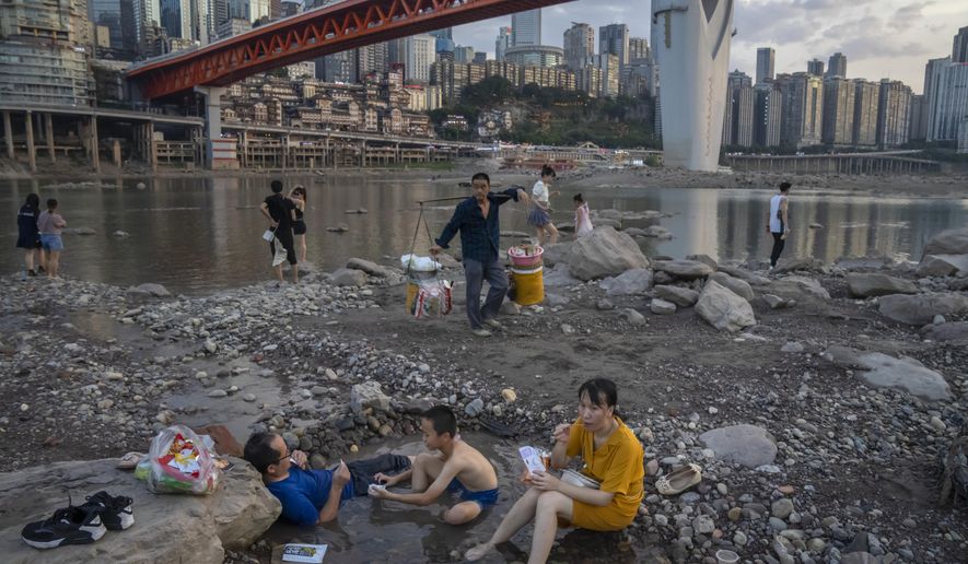 People sit in a shallow pool of water in the riverbed of the Jialing River, a tributary of the Yangtze, in southwestern China&#39;s Chongqing Municipality, Saturday, Aug. 20, 2022. The very landscape of Chongqing, a megacity that also takes in surrounding farmland and steep and picturesque mountains, has been transformed by an unusually long and intense heat wave and an accompanying drought. (AP Photo/Mark Schiefelbein)