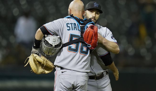 Miami Marlins catcher Jacob Stallings, left, hugs relief pitcher Tanner Scott, right, after the team&#x27;s 5-3 victory against the Oakland Athletics in Oakland, Calif., Tuesday, Aug. 23, 2022. (AP Photo/Godofredo A. Vásquez)