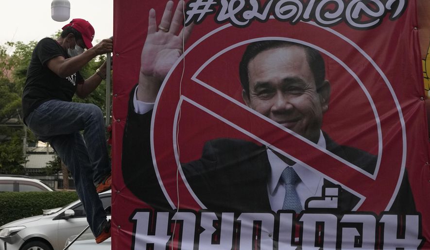 An anti-government protester climb on car beside a poster of Prime Minister Prayuth Chan-ocha in Bangkok, Thailand, Wednesday, Aug. 24, 2022. Thailand&#x27;s Constitutional Court ruled Wednesday that Prime Minister Prayuth Chan-ocha must suspend his active duties while the court decides whether he has overstayed his legal term in office. The poster reads &amp;quot;Time is over.&amp;quot; (AP Photo/Sakchai Lalit)