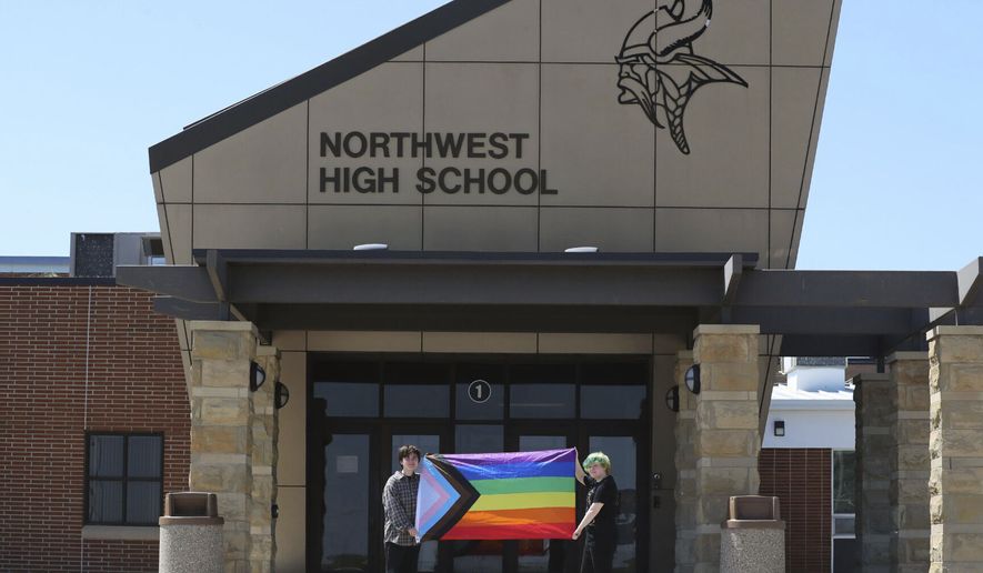 Former Viking Saga newspaper staff members Marcus Pennell, left, and Emma Smith, right, display a pride flag outside of Northwest High School in Grand Island, Neb., July 20, 2022. Administrators of a Nebraska public school have shuttered the schools award-winning student newspaper, just days after its last edition that included articles and editorials on LGBTQ issues. (McKenna Lamoree/The Independent via AP)