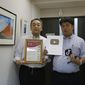 Daikyo Security Chief Executive Daisuke Sakurai, right, and General Manager Tomohiko Kojima hold the awards they have won recently for their Tik Tok videos in the hallway of their Tokyo headquarters office of Daikyo Security Co. in Tokyo Monday, Aug. 22, 2022. They’re your run-of-the-mill Japanese “salarymen,” but the chief executive and general manager at a tiny Japanese security company are among the nation’s biggest TikTok stars, drawing 2.7 million followers and 54 million likes, and honored with awards as a trend-setter on the video-sharing app. (AP Photo/Yuri Kageyama)