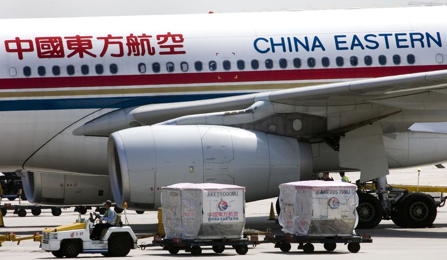 A carter drives past a China Eastern airliner parked at the Beijing International Airport in Beijing, China on Aug. 29, 2007. The U.S. government is suspending 26 flights by Chinese airlines from the United States to China in a dispute over anti-virus controls after Beijing suspended flights by American carriers. (AP Photo/Andy Wong, File)