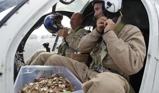 FILE - USDA wildlife specialist Will Guigou, right, and pilot Thomas Taylor prepare to distribute packets of baited rabies vaccine by helicopter from a container between Guigou&#39;s knees Tuesday, Oct. 22, 2013, at Chattanooga Metropolitan Airport&#39;s Lovell Field in Chattanooga, Tenn.  The U.S. government has begun scattering millions of packets of oral rabies vaccine from helicopters and planes over 13 states from Maine to Alabama. The major aim is to keep raccoons from spreading their strain of the deadly virus to states where it hasn&#39;t been found or isn&#39;t widespread, said field trial coordinator Jordona Kirby.  ( Doug Strickland/Chattanooga Times Free Press via AP)