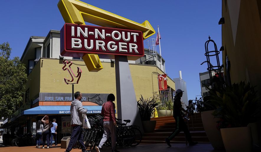 Pedestrians walk below an In-N-Out Burger restaurant sign in San Francisco, Thursday, Aug. 25, 2022. More than a half-million California fast food workers are pinning their hopes on a groundbreaking proposal that would give them increased power and protections. (AP Photo/Jeff Chiu)
