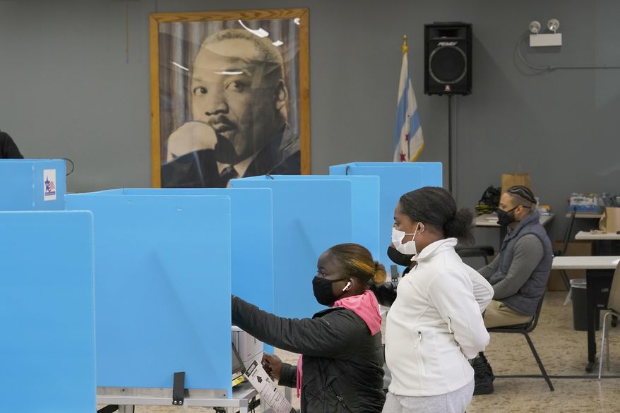 FILE - Jeniya Garrett, right, watches her aunt Catherina Neal vote on Election Day on Nov. 3, 2020, at the Dr. Martin Luther King Community Center in the Bronzeville neighborhood of Chicago. Illinois voters have the chance to sign up to send their ballots for the November 2022 election and spring elections by mail — forever. Elections officials are sending applications for permanent permission to vote by mail to each of the state’s 8 million registered voters. (AP Photo/Charles Rex Arbogast, File)