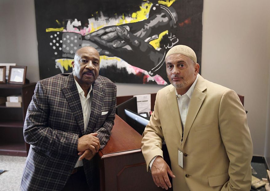 In this Wednesday, Aug. 10, 2022 photo, Fred Hodges, left, and Da'ee McKnight at their workplace, Family ReEntry, a reentry support group aiming to break cycles of violence, crime and incarceration in Bridgeport, Conn. Hodges and McKnight are former Connecticut inmates who have been paying for cost of their incarceration. (AP Photo/Jessica Hill)