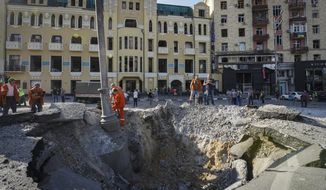 A view of a crater from a night Russian rocket attack, near to damaged buildings in downtown Kharkiv, Ukraine, Saturday, Aug. 27, 2022. (AP Photo/Andrii Marienko)