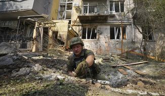 A Ukrainian serviceman collects fragments in the crater to determine the type of ammunition after a Russian attack that damaged some buildings in Kharkiv, Ukraine, Tuesday, Aug. 30, 2022. A surge in fighting on the southern front line and a Ukrainian claim of new attacks on Russian positions fed speculation Tuesday that a long-expected counteroffensive has started to try to turn the tide of the war. (AP Photo/Andrii Marienko)