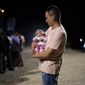 A migrant man from Colombia holds his baby daughter after crossing into the United States near the end of a border wall Tuesday, Aug. 23, 2022, near Yuma, Ariz. A border wall with Mexico isn&#39;t the issue it was during Donald Trump&#39;s presidency but plans for more barriers in Yuma, Ariz., is a reminder of obstacles that the federal government always faces: difficulty working on tribal lands and private property. (AP Photo/Gregory Bull)