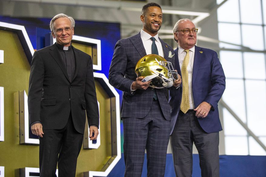 Notre Dame head football coach Marcus Freeman holds a helmet while posing for a portrait with University president John I. Jenkins, left, and Athletic Director Jack Swarbrick during a news conference on Dec. 6, 2021, at the Irish Athletic Center in South Bend, Ind. Swarbrick told The Associated Press on Tuesday, Aug. 30, 2022, that the Fighting Irish&#x27;s position is even stronger now than when he stepped into the job in 2008, bolstered by success on the football field and investments in the program. (Michael Caterina/South Bend Tribune via AP, File) **FILE**