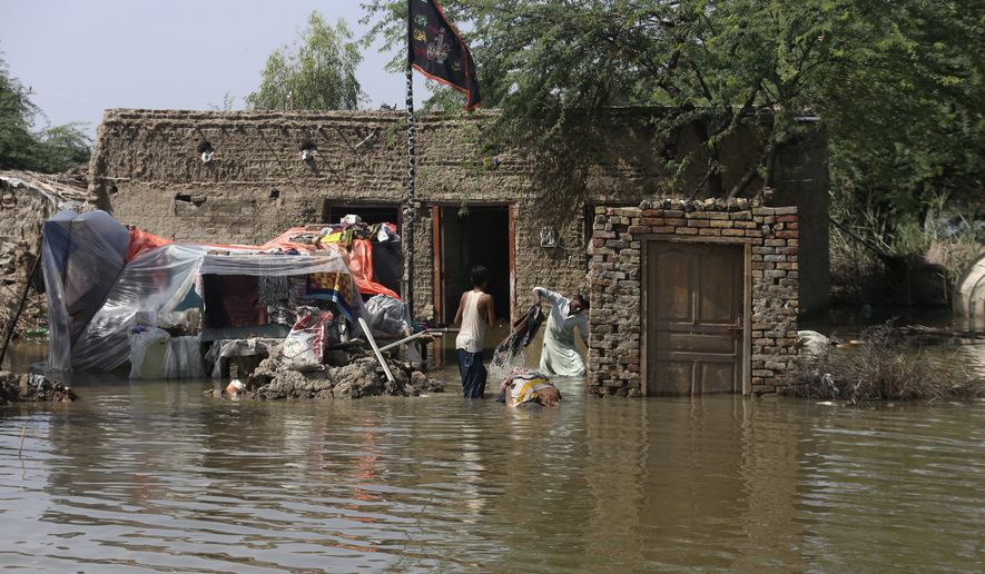A family salvages belongings from their flood-hit home in Shikarpur district of Sindh province, of Pakistan, Wednesday, Aug. 31, 2022. Officials in Pakistan raised concerns Wednesday over the spread of waterborne diseases among thousands of flood victims as flood waters from powerful monsoon rains began to recede in many parts of the country. (AP Photo/Fareed Khan)