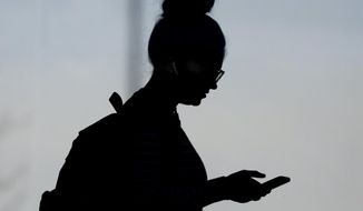 A woman checks her phone in Orem, Utah, on Nov. 14, 2019. A survey of people ages 16 to 40 finds that millennials and Generation Z follow the news, but they aren&#39;t that happy with what they&#39;re seeing. The study conducted by The Associated Press-NORC Center for Public Affairs Research and the American Press Institute says 79% of people follow news daily, contrary to perceptions that many are tuned out. (AP Photo/Rick Bowmer, File)