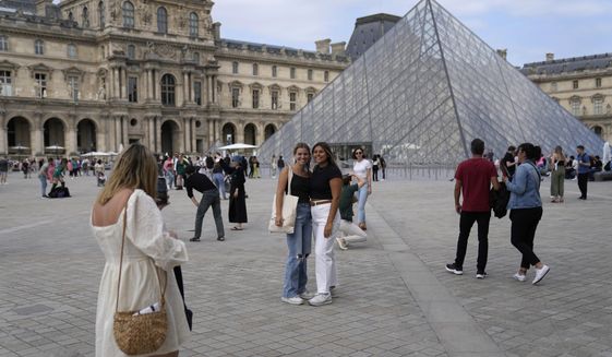 Tourists take pictures in front of the Pyramide in the Louvre Museum courtyard, in Paris, France, Monday, June 20, 2022. Tourism came back with a vengeance to France this summer, sending revenues over pre-pandemic levels, according to preliminary government estimates released this week. Crowds packed Paris landmarks and Riviera beaches, notably thanks to an influx of Americans benefiting from the weak euro, but also British and other European visitors reveling in the end of pandemic restrictions. (AP Photo/Francois Mori, File)