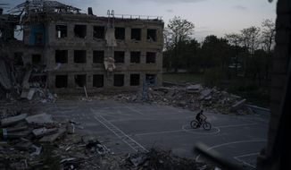A man cycles through a courtyard of the destroyed School Number 23 after a Russian attack occurred in the second half of July, in Kramatorsk, Ukraine, Saturday, Aug. 27, 2022. (AP Photo/Leo Correa)  **FILE**