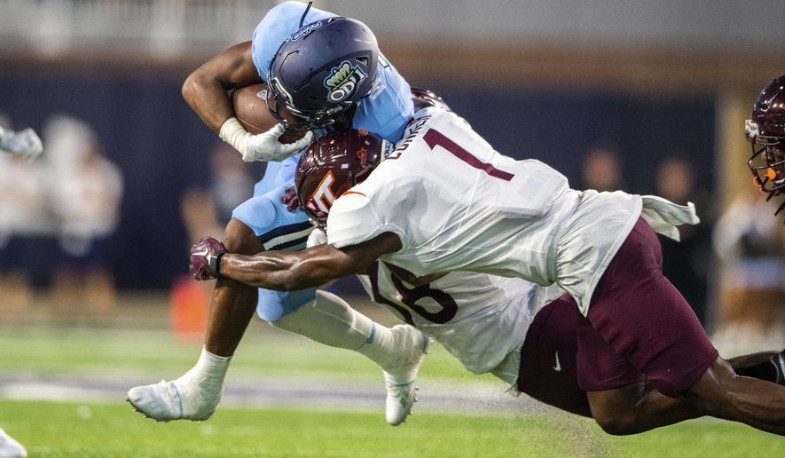 Old Dominion running back Keshawn Wicks, top, is brought down by Virginia Tech linebacker Jayden McDonald (38) and defensive back Chamarri Conner (1) during an NCAA college football game on Friday, Sept. 2, 2022, in Norfolk, Va. (AP Photo/Mike Caudill)