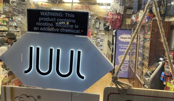 A Juul electronic cigarette sign hangs in the front window of a bodega convenience store in New York City on June 25, 2022. In a deal announced Tuesday, Sept. 6, 2022, electronic cigarette maker Juul Labs will pay nearly $440 million to settle a two-year investigation by 33 states into the marketing of its high-nicotine vaping products, which have long been blamed for sparking a national surge in teen vaping. (AP Photo/Ted Shaffrey, File)