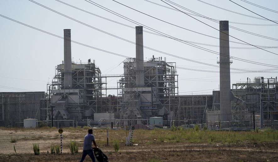 A man pushes a stroller near the AES power plant in Redondo Beach, Calif., Wednesday, Sept. 7, 2022. A record heat wave put California in a fossil fuel conundrum: The state has had to rely more heavily on natural gas to produce electricity and avoid power outages while Gov. Gavin Newsom's administration moves toward ending the use of oil and gas. (AP Photo/Jae C. Hong)