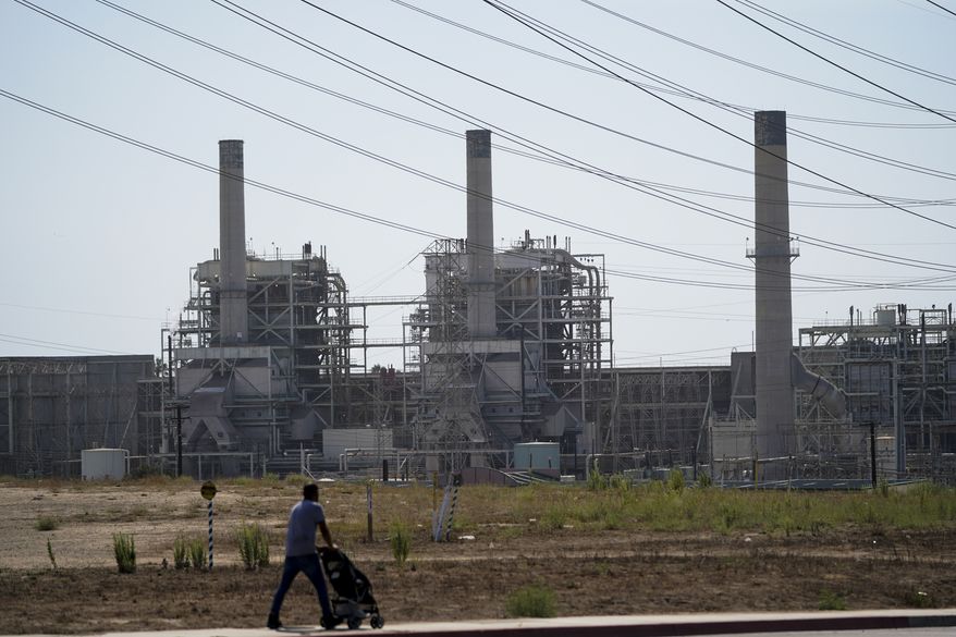A man pushes a stroller near the AES power plant in Redondo Beach, Calif., Wednesday, Sept. 7, 2022. A record heat wave put California in a fossil fuel conundrum: The state has had to rely more heavily on natural gas to produce electricity and avoid power outages while Gov. Gavin Newsom's administration moves toward ending the use of oil and gas. (AP Photo/Jae C. Hong)