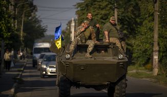 Ukrainian army soldiers sit on an armour military vehicle as they drive in Bucha, near in Kyiv, Ukraine, Thursday, Sept. 8, 2022. (AP Photo/Emilio Morenatti)