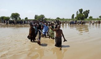 Victims of unprecedented flooding from monsoon rains line up to receive relief aid organized by the Edhi Foundation, in the Ghotki District of Sindh Pakistan, Wednesday, Sept. 7, 2022. (AP Photo/Fareed Khan)