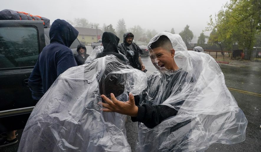 Members of the Ornelas family put on plastic raincoats as wind and rain pummel the area Friday, Sept. 9, 2022, in Julian, Calif. A tropical storm nearing Southern California has brought fierce mountain winds, high humidity, rain and the threat of flooding to a region already dealing with wildfires and an extraordinary heat wave. (AP Photo/Gregory Bull)