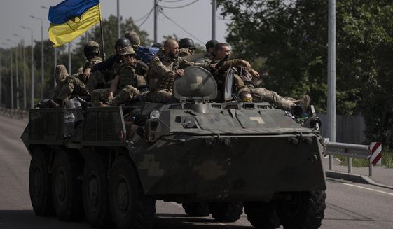 Ukrainian servicemen ride atop of an armored vehicle on a road in Donetsk region, eastern Ukraine, Sunday, Aug. 28, 2022. As the war slogs on, a growing flow of Western weapons over the summer is now playing a key role in the counteroffensive, helping Ukraine significantly boost its precision strike capability. (AP Photo/Leo Correa, File)
