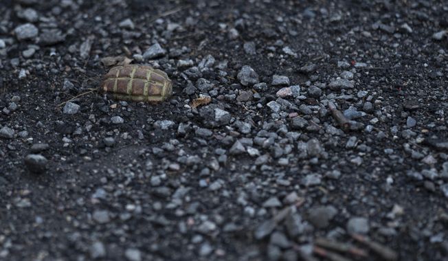 A hand grenade is seen on the road at the entrance of the freed village of Hrakove, Ukraine, Tuesday, Sept. 13, 2022. (AP Photo/Leo Correa) ** FILE **