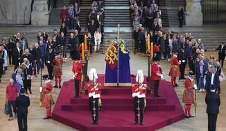 Members of the public pay their respects as they walk past the coffin of Queen Elizabeth II, draped in the Royal Standard with the Imperial State Crown and the Sovereign&#39;s orb and sceptre, lying in state on the catafalque in Westminster Hall, London, Thursday, Sept. 15, 2022. (Yui Mok/Pool Photo via AP)