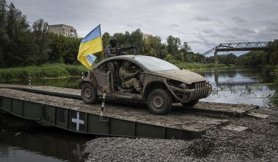 Ukrainian paratroopers drive on the vehicle with Ukrainian flag on the pantone bridge across Siverskiy-Donets river in the recently retaken area of Izium, Ukraine, Wednesday, Sept. 14, 2022. (AP Photo/Evgeniy Maloletka)