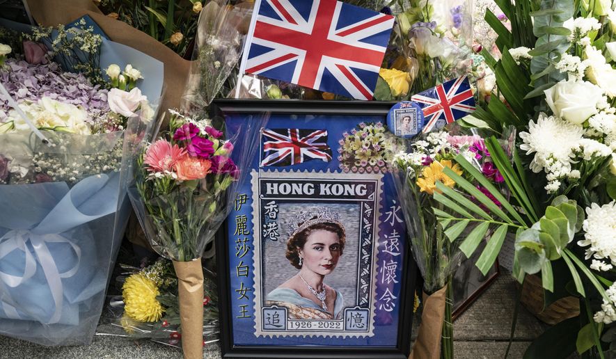 Flowers and a photograph are placed for Queen Elizabeth II outside the British Consulate in Hong Kong, Friday, Sept. 16, 2022. In Britain, Thousands of mourners waited for hours Thursday in a line that stretched for almost 5 miles (8 kilometers) across London for the chance to spend a few minutes filing past Queen Elizabeth II&#39;s coffin while she lies in state. (AP Photo/Anthony Kwan)