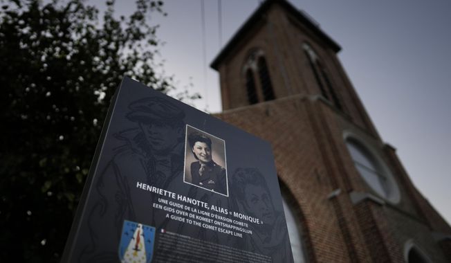 An information board with a photo of Henriette Hanotte stands next to the local church in the center of the town of Bachy, France, Friday, Sept. 16, 2022. Hanotte was a Belgian resistance member during World War II and from the age of nineteen aided the escape of nearly 140 airmen from occupied Belgium into France as part of the Comet Line. (AP Photo/Virginia Mayo)