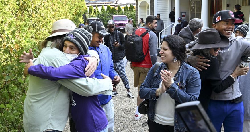 Carlos Munoz reaches out to hug Larkin Stallings of Vineyard Haven, Mass., as the immigrants prepare to leave St. Andrews in Edgartown, Mass., Friday, Sept. 16, 2022. Florida Gov. Ron DeSantis took the playbook of a fellow Republican, Texas Gov. Greg Abbott, to a new level by catching officials flat-footed in Martha's Vineyard, Mass., with two planeloads of Venezuelan migrants. On Friday, the migrants were being moved voluntarily to a military base on nearby Cape Cod, Mass. (Ron Schloerb/Cape Cod Times via AP)