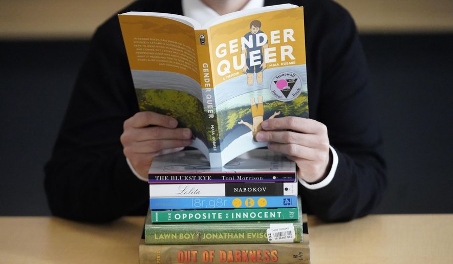 Amanda Darrow, director of youth, family and education programs at the Utah Pride Center, poses with books that have been the subject of complaints from parents in Salt Lake City on Dec. 16, 2021. The wave of attempted book banning and restrictions continues to intensify, the American Library Association reported Friday. Numbers for 2022 already approach last year's totals, which were the highest in decades. (AP Photo/Rick Bowmer, File)