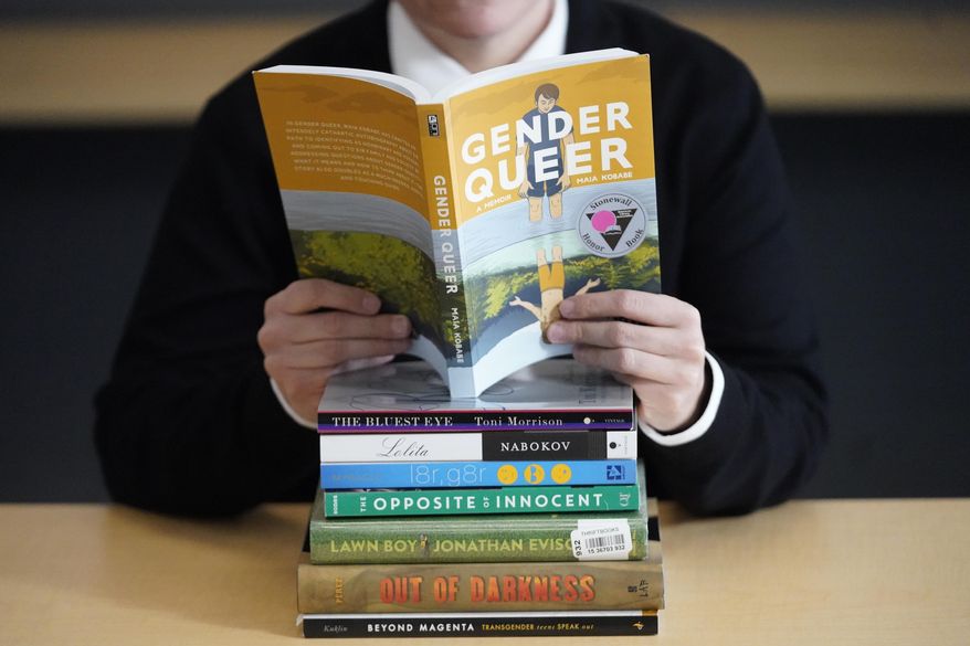 Amanda Darrow, director of youth, family and education programs at the Utah Pride Center, poses with books that have been the subject of complaints from parents in Salt Lake City on Dec. 16, 2021. The wave of attempted book banning and restrictions continues to intensify, the American Library Association reported Friday. Numbers for 2022 already approach last year's totals, which were the highest in decades. (AP Photo/Rick Bowmer, File)