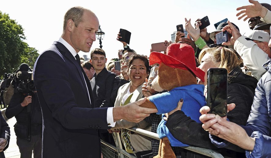 Britain's Prince William shakes hands with a Paddington Bear toy as he meets members of the public in the queue along the South Bank, near Lambeth Bridge, London, on Saturday, Sept. 17, 2022, as they wait to view Queen Elizabeth II lying in state ahead of her funeral on Monday. (Aaron Chown/PA via AP) ** FILE **