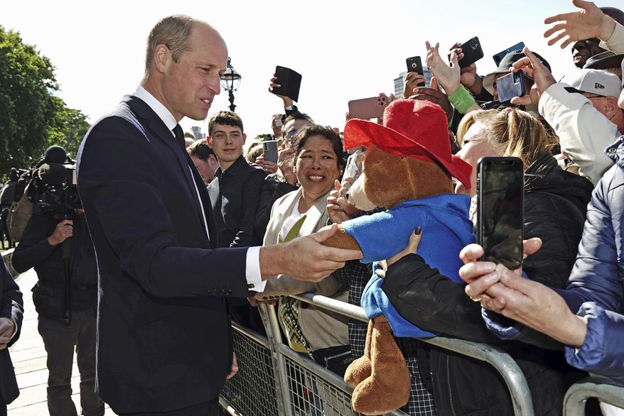 Britain's Prince William shakes hands with a Paddington Bear toy as he meets members of the public in the queue along the South Bank, near Lambeth Bridge, London, on Saturday, Sept. 17, 2022, as they wait to view Queen Elizabeth II lying in state ahead of her funeral on Monday. (Aaron Chown/PA via AP) ** FILE **