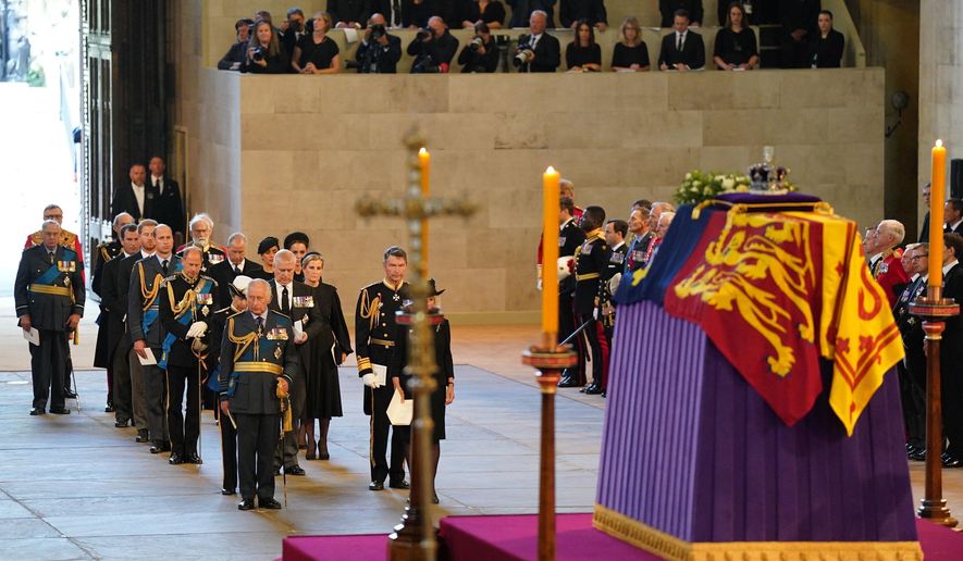 Photographers and reporters can be seen in background, upper right, with the coffin of Queen Elizabeth II on the catafalque in Westminster Hall, London, Wednesday Sept. 14, 2022. Plans by news organizations that have been in place for years — even decades — to cover the death of Queen Elizabeth II were triggered and tested when the event took place. London has been inundated with journalists, with more headed to the city for the funeral services on Monday. ( Jacob King/Pool via AP, File)